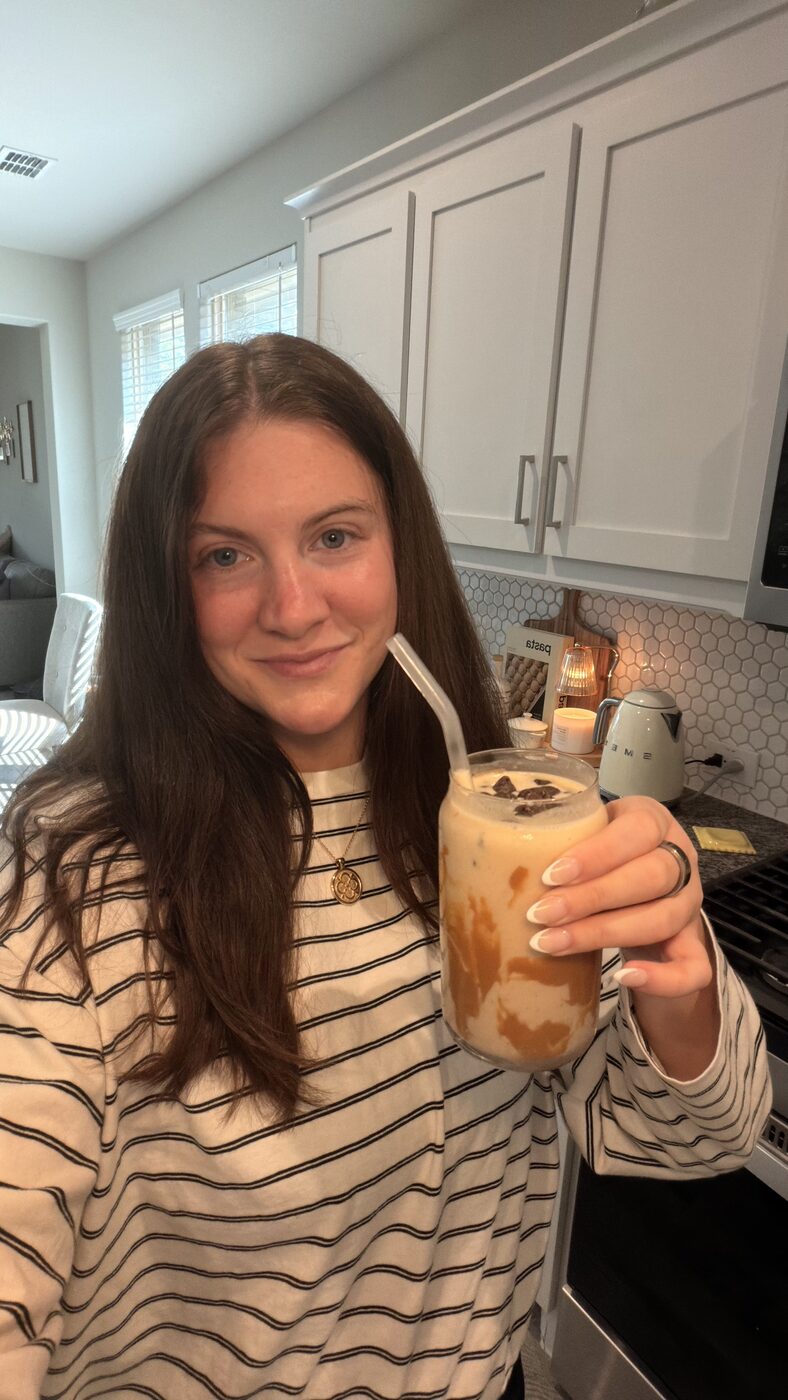 Caitlin with an iced coffee at home